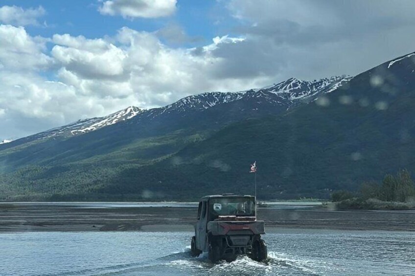 A vehicle on a frozen lake with mountains in the background. 4