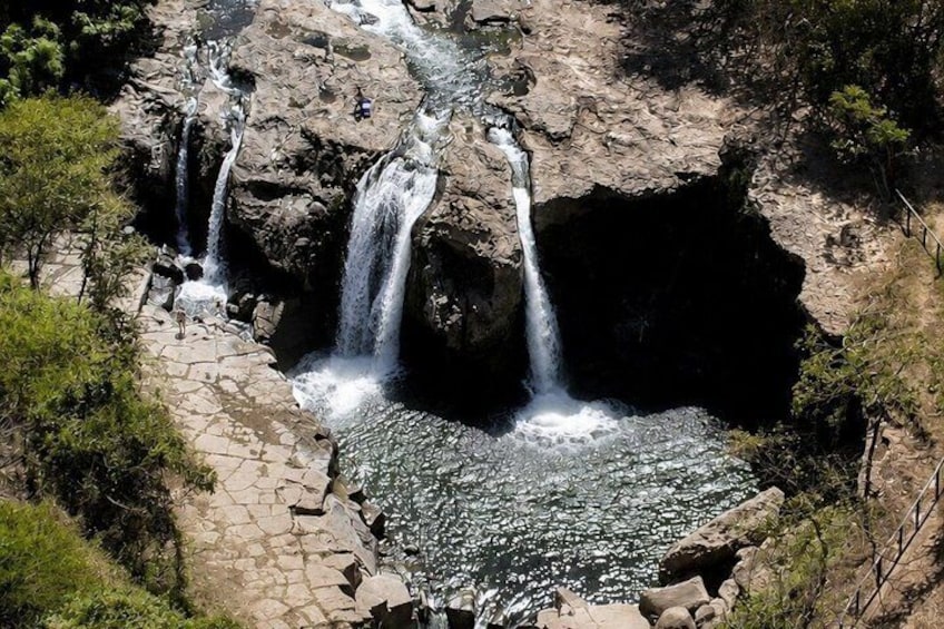 A multi-tiered waterfall cascading over rocks into a pool. 1