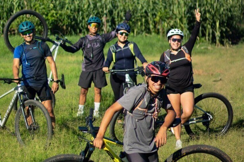 A group of cyclists in a grassy field with bicycles and a tire in the foreground. 5