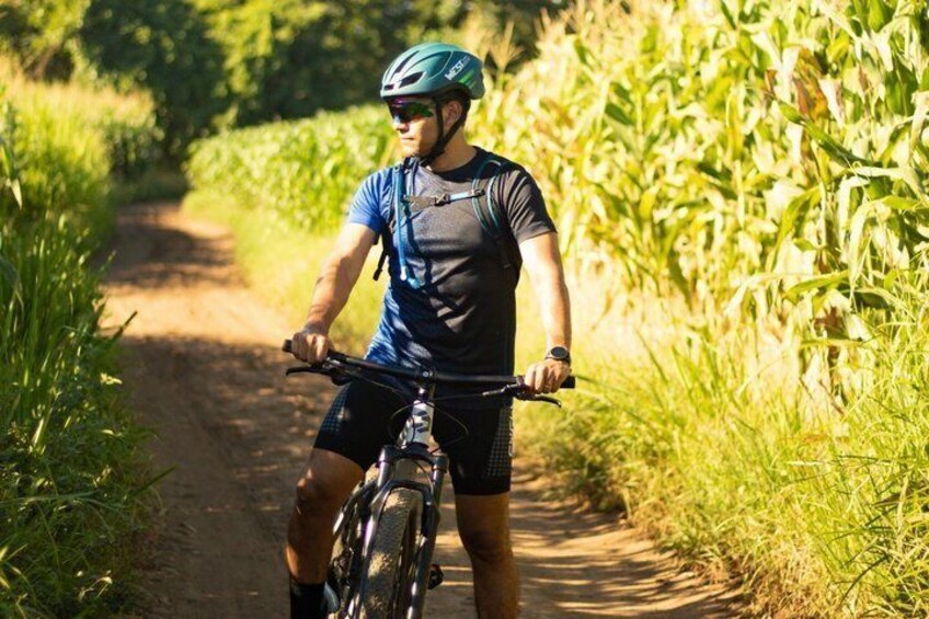 A person riding a mountain bike on a dirt path surrounded by greenery. 2