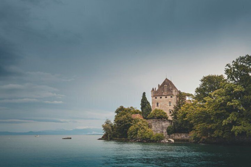 A castle on a cliff by a calm lake with a boat in the distance. 1