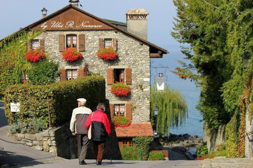 A stone building with red flowers and a sign reading 'By Ulia R. Novarozu.' 4