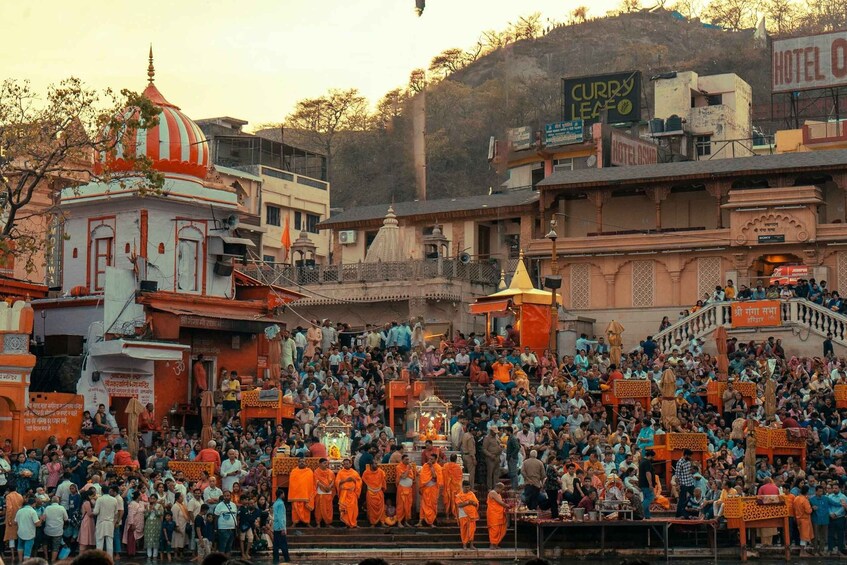 A crowded temple with orange-robed monks, a large crowd, and traditional architecture. 4