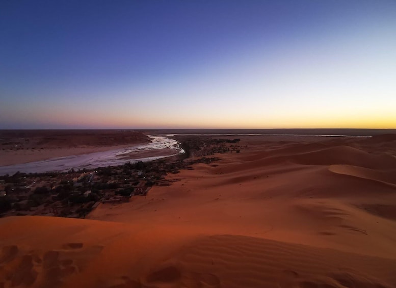 A desert landscape with sand dunes and a river. 3
