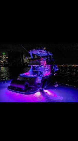 A boat with purple lighting on a body of water at night. 5