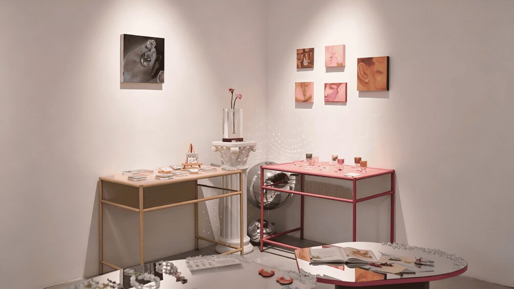 An art gallery with paintings on the walls, a table with art supplies, and a disco ball. 3