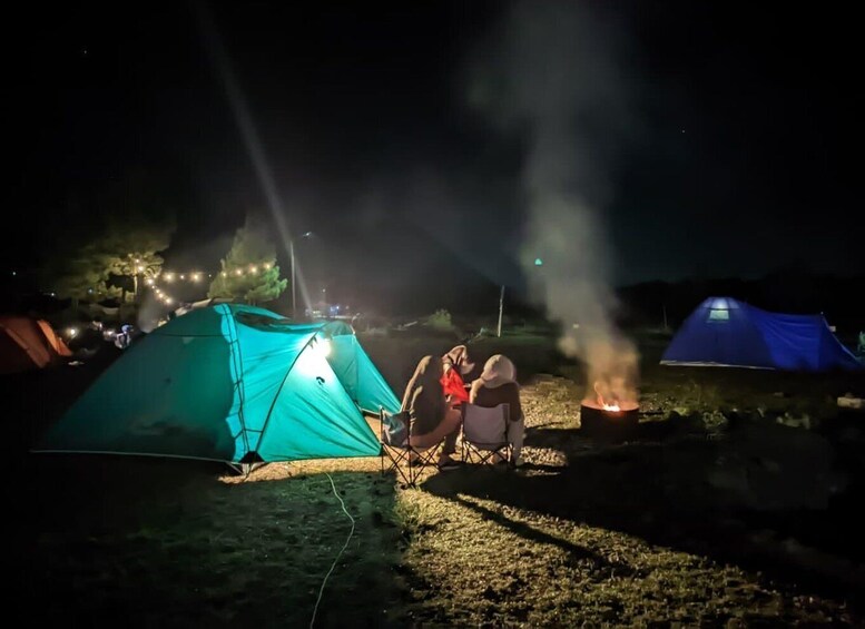 A camping scene at night with tents and a campfire. 1