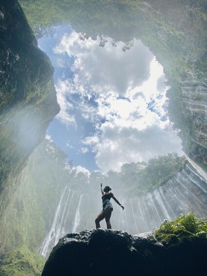 A person standing on a rock with waterfalls in the background. 4