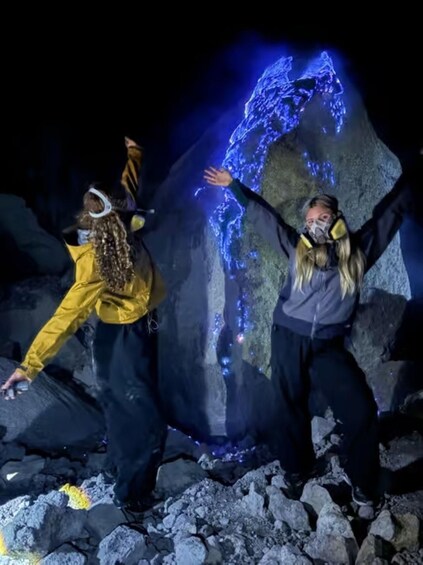 Two people interacting with a large illuminated rock formation. 3