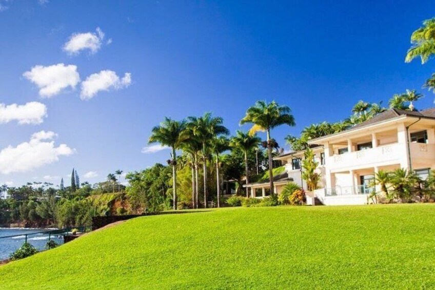 A coastal property with a grassy lawn, palm trees, and a large house. 1