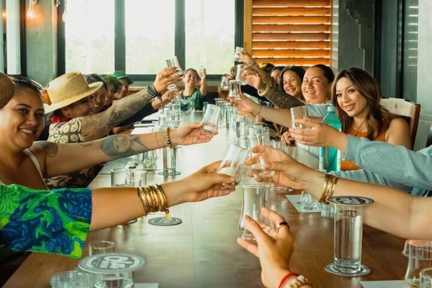 A group of people toasting with drinks around a table in a well-lit indoor setting. 5