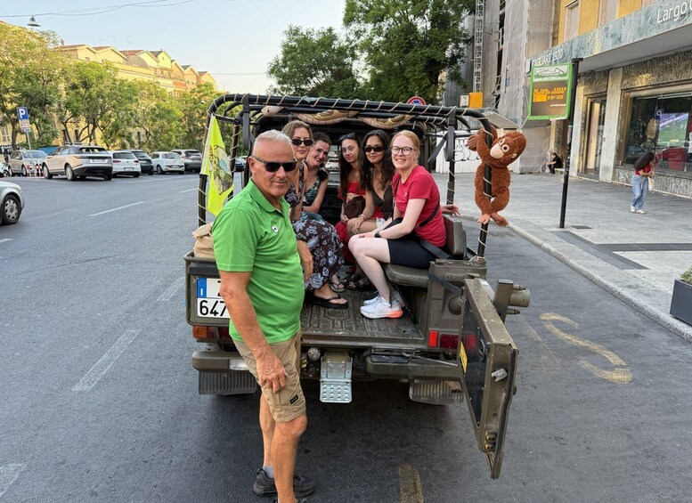A group of people on a vehicle with a monkey figure on the back, parked on a street with buildings and parked cars. 2