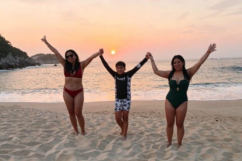 Three people on a beach at sunset, holding hands. 3