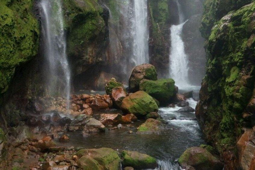 A waterfall surrounded by moss-covered rocks. 2