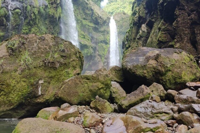 A waterfall surrounded by large rocks and lush greenery. 4