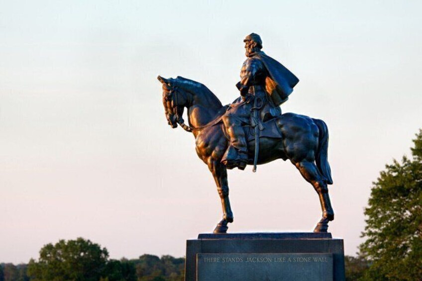 A bronze statue of a man on horseback mounted on a pedestal with a plaque. 1