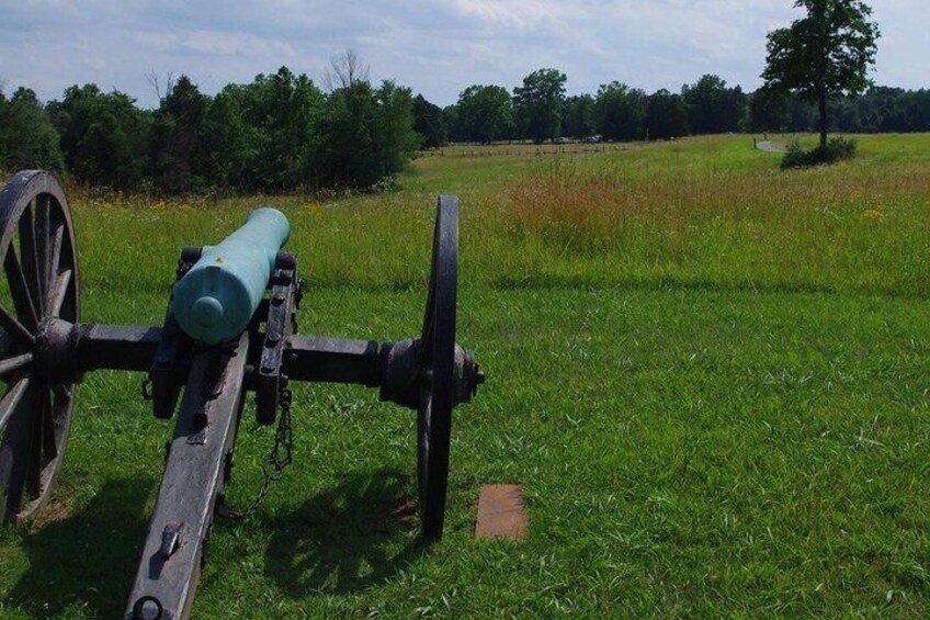 A cannon in a grassy field with trees in the background. 4