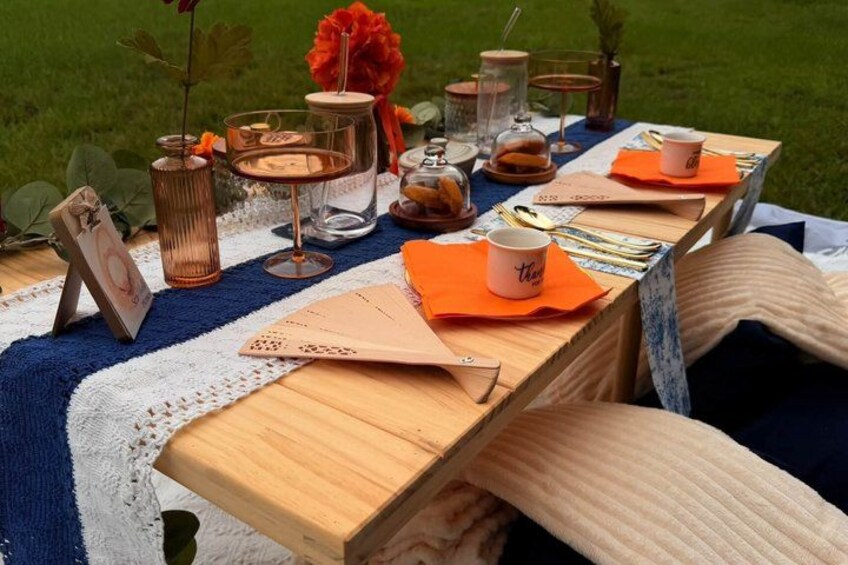 A wooden picnic table with orange napkins, a picture frame, and a card game set. 2