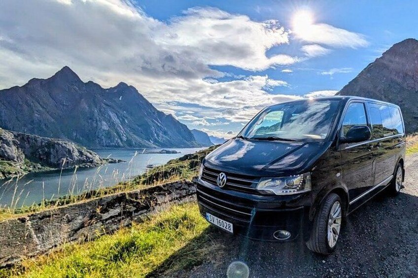 A black Volkswagen van parked on a road with a mountainous landscape in the background. 3