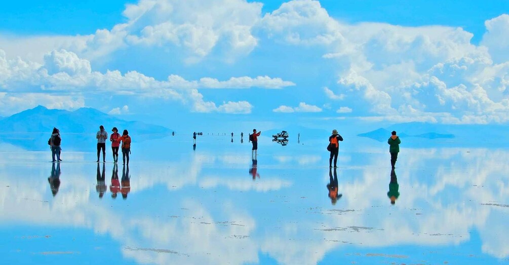 A group of people standing on a reflective surface with mountains in the background. 5