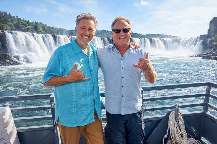Two people on a boat with a waterfall in the background. 3