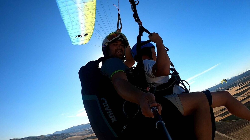 A person paragliding with a parachute, holding onto a control bar, and wearing a helmet. 4