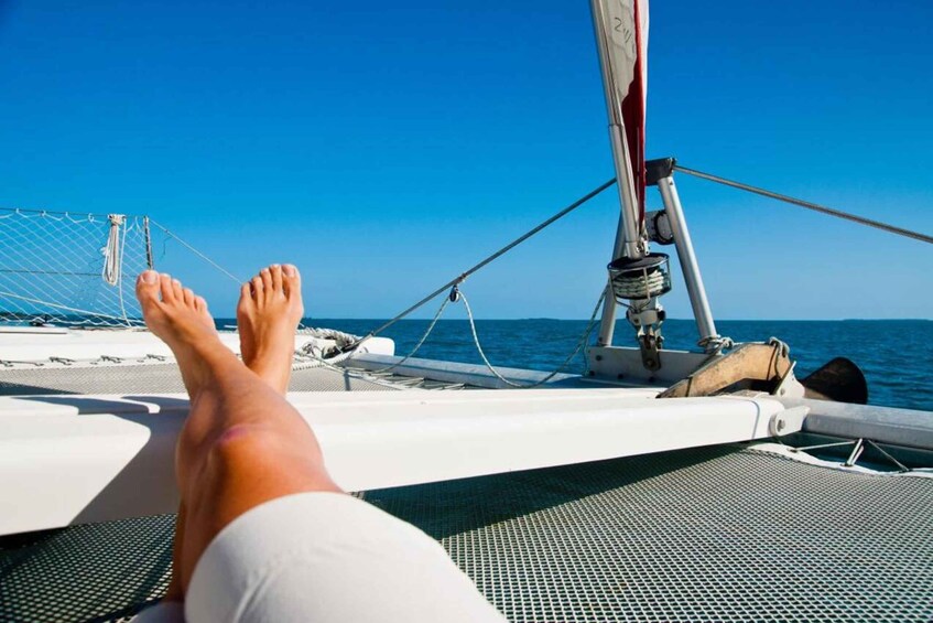 A person's legs resting on a boat's deck, with the ocean and sky in the background. 1