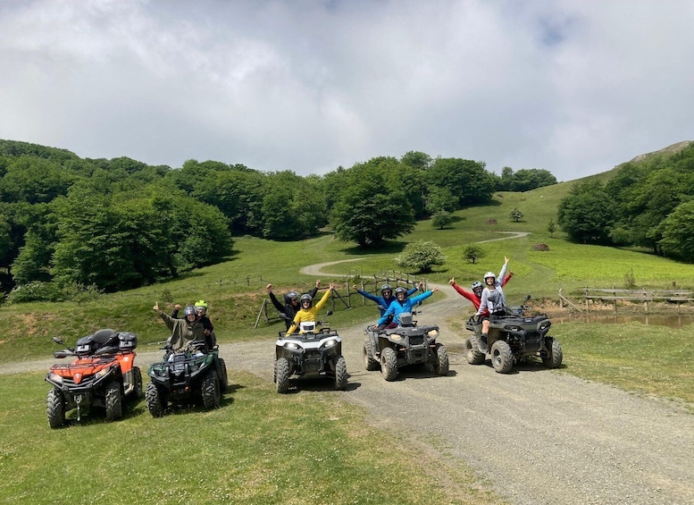Four people on ATVs on a gravel path with green hills and trees in the background. 1
