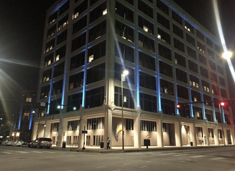 A multi-story building with illuminated windows and a street in front. 5