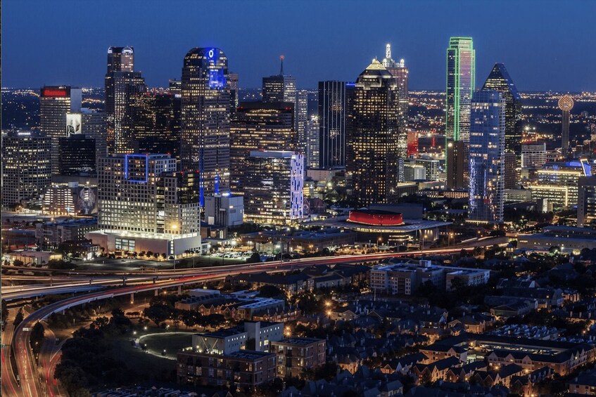 A city skyline at night with illuminated buildings and a highway with light trails. 2