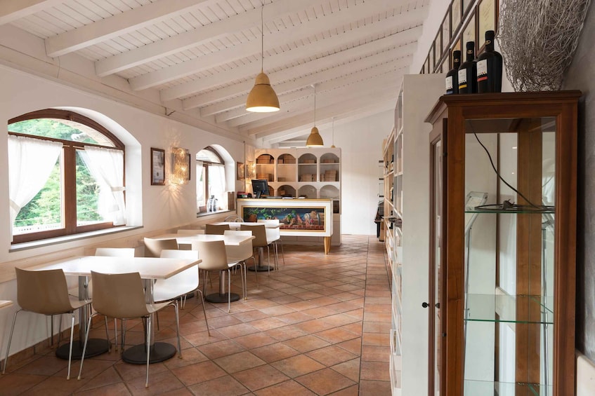 A restaurant interior with white walls, tiled floor, and a dining area with tables and chairs. 2