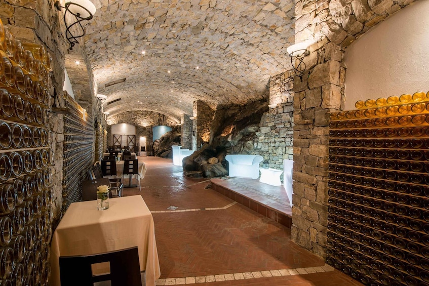 A wine cellar with stone walls, wine racks, and a table with a vase. 4