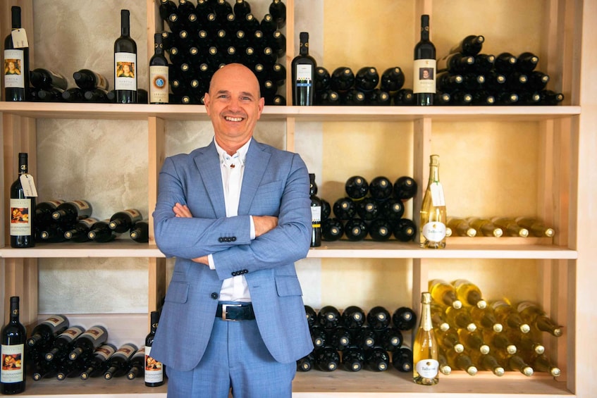 A man standing in front of shelves filled with wine bottles. 5