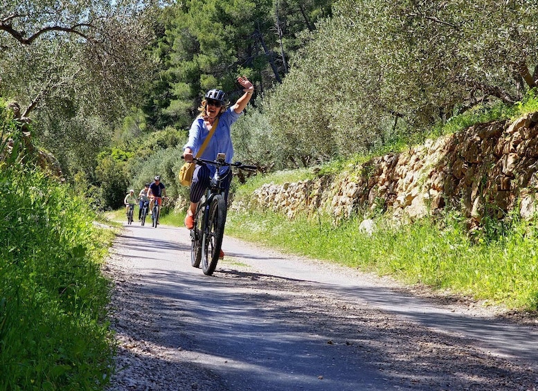 A group of cyclists on a gravel road surrounded by greenery and trees. 1
