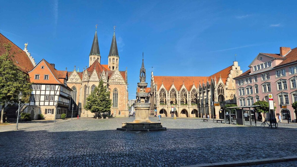A cobblestone square with historic buildings, a church, and a fountain. 4