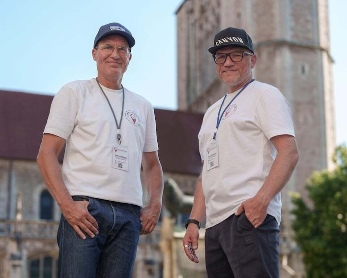 Two men standing in front of a building with a clock tower. 1