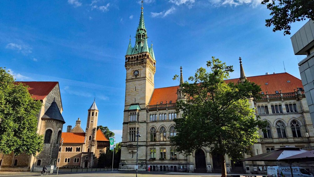 A historic building with a clock tower and a church with a spire. 2