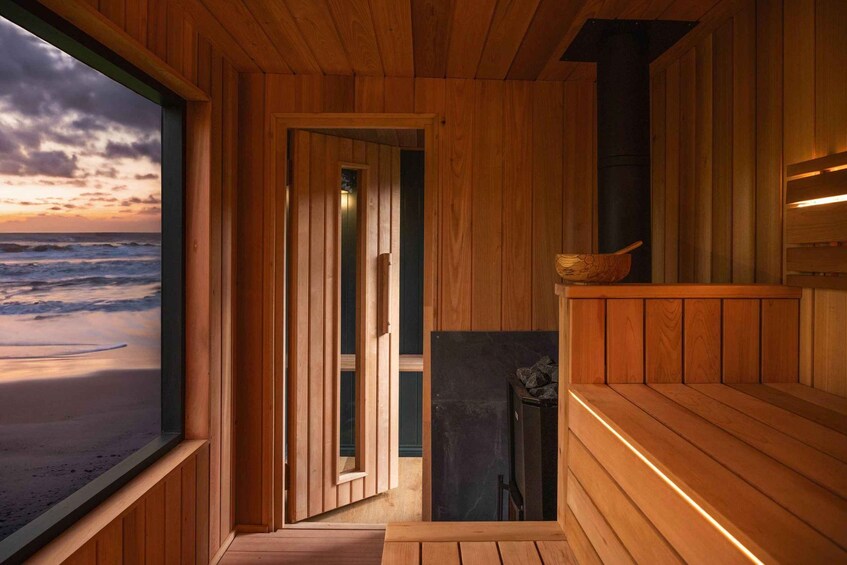 A wooden sauna with a view of the ocean at sunset. 1