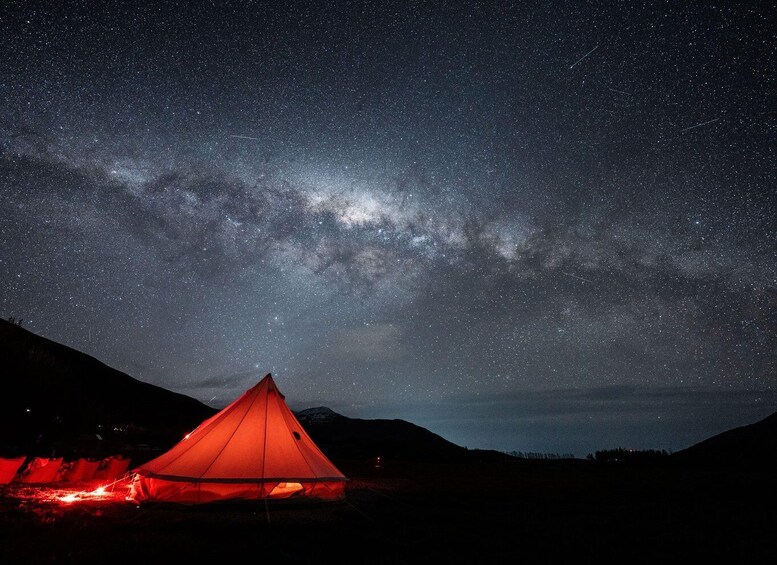 A red tent under a starry night sky with the Milky Way visible. 1
