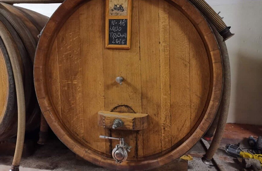 A wooden barrel with a chalkboard sign, metal fittings, and hoses. 2