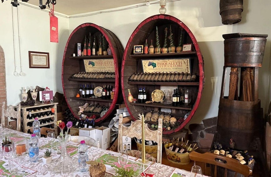 A wine cellar with wooden barrels and shelves stocked with wine bottles. 5