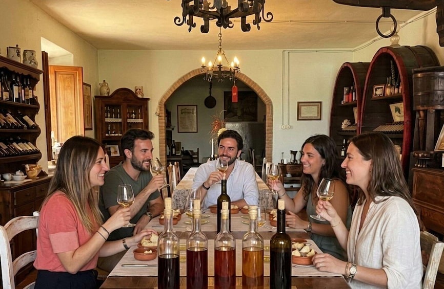 A group of people toasting with wine glasses at a dinner table in a warmly lit room with a chandelier. 1