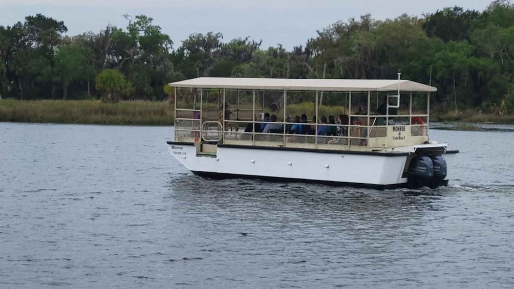 A white boat with a covered deck, named 'Monroe,' on a calm body of water. 3