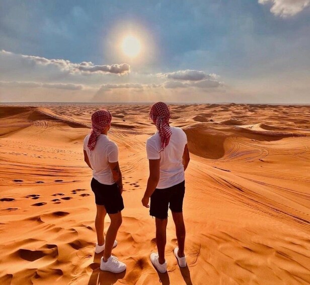 Two people standing on a desert sand dune with a clear sky and sun in the background. 5