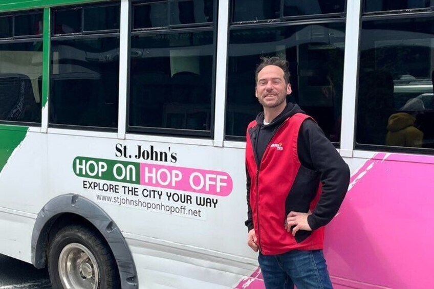 A person standing next to a bus with 'St. John's Hop On Hop Off' written on it. 3
