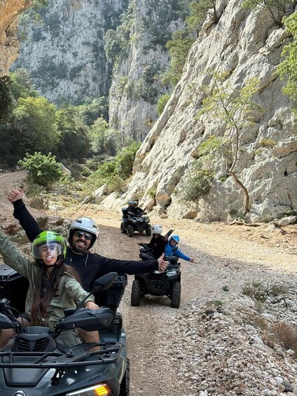 A group of people on ATVs on a rocky trail with cliffs in the background. 1