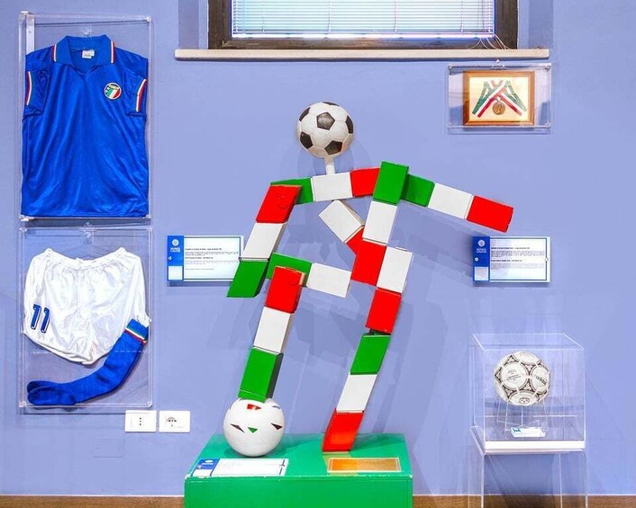 A soccer player figurine, a blue jersey, a white jersey, and a framed picture on a wall. 4