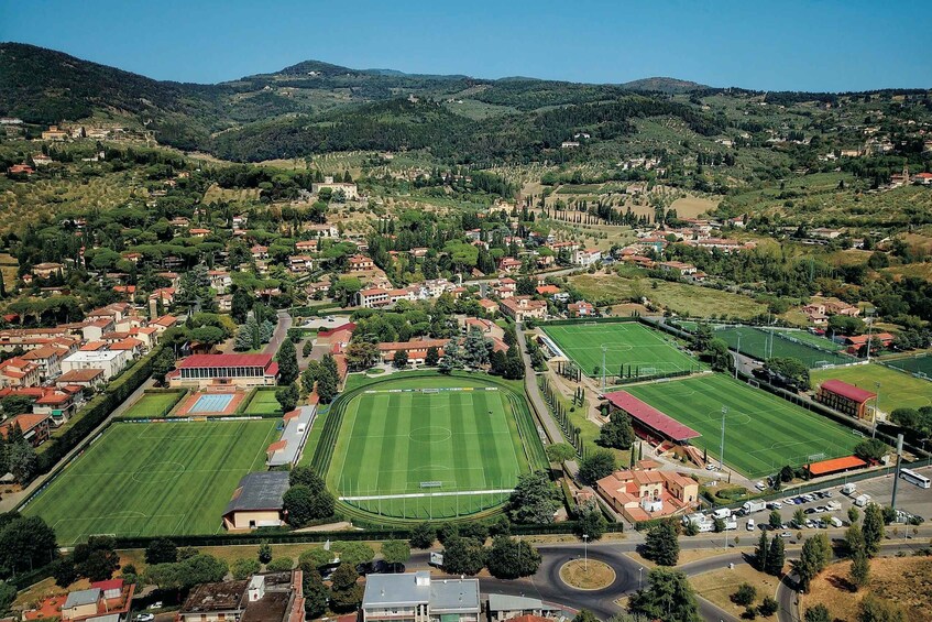 A mountainous town with residential areas, green fields, and multiple soccer fields. 2
