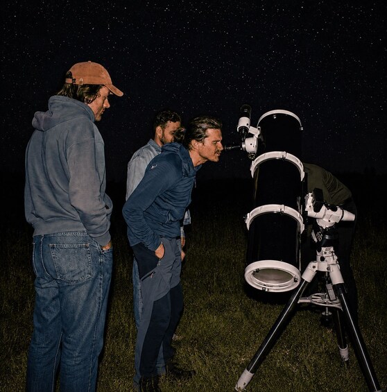 Three people observing the night sky through telescopes. 4