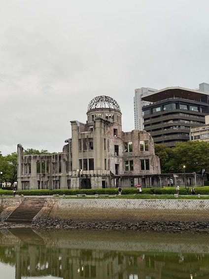 A historic building with a large dome structure, surrounded by modern buildings and a body of water reflecting the architecture. 3